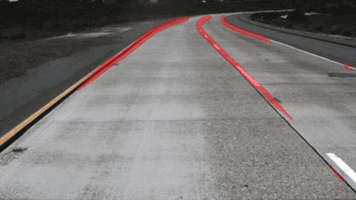 Frame from a highway clip with the predicted lane mask overlaid in red